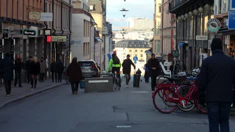 Man-rides-bike-in-middle-of-busy-pedestrian-street,-Stockholm,-Sweden