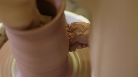 Clay-vase-being-shaped-smooth-with-wet-sponge-on-studio-pottery-wheel-turntable