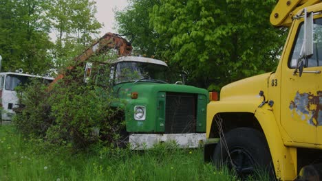 Slow-motion-of-a-vintage-school-bus-and-a-large-vintage-truck-sitting-in-the-forest-rotting-away