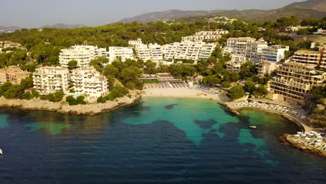 Approaching-drone-shot-of-Playa-Lletas,-also-known-as-Lletes-beach-resort-located-in-the-Mediterranean-island-of-Mallorca-off-the-coast-of-Spain