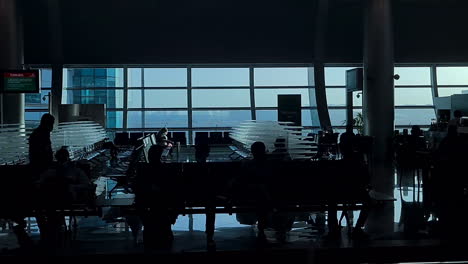 Abu-Dhabi-International-Airport-Gates-and-Terminal-With-People-in-Waiting-Area,-View-From-Moving-Walkway