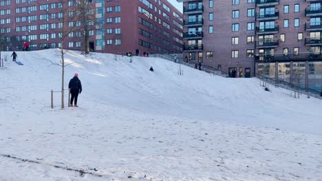 Children-go-down-snowy-hill-on-toboggans-in-park-in-wintertime-Sweden
