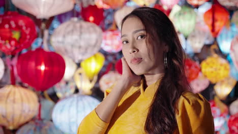 Close-up-portrait-of-Vietnamese-woman-in-traditional-yellow-dress-surrounded-by-colorful-lanterns