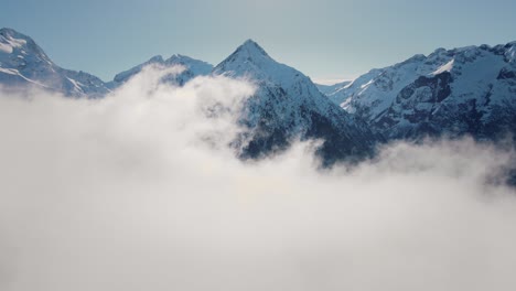 Drone-video-flying-through-the-clouds-towards-a-snowy-mountain-range