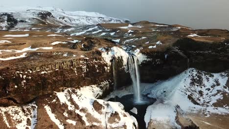 Vista-Aérea-Por-Drones-De-La-Majestuosa-Cascada-En-La-Invernal-Islandia,-Tierra-De-Fuego-Y-Hielo