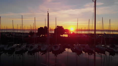 Spannender-Sonnenaufgangsflug-über-Einen-Bootshafen-Auf-Der-Kalifornischen-Halbinsel,-Seevögel,-Segelschiffe,-Luftaufnahmen-Und-Eine-Strahlende-Morgensonne,-Die-Sich-In-Der-Ruhigen-Bucht-Von-San-Francisco-Spiegelt