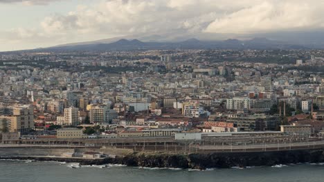 Catania-City,-Sicily-with-Mt-Etna-in-background,-drone-establishing-shot-warm-afternoon-light