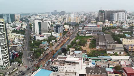 Drohnenaufnahme-Von-Autos,-Die-Durch-Eine-Metropole-In-Indien-Voller-Gebäude-Fahren