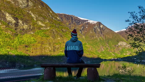 Lonely-man-surrounded-by-nature-watching-cruise-ship-on-fjord-water-in-Norway