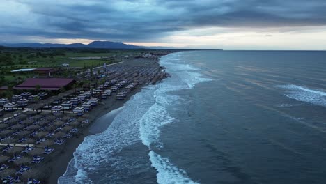 Arial-view:-Early-Morning-Coastal-Flight:-Waves,-Mountains,-and-Beachfront-Serenity