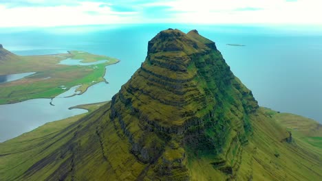 Aerial-footage-captured-by-a-cinematic-4K-drone-offers-a-distinctive-top-down-perspective-of-the-Kirkjufell-peak,-set-amidst-the-surrounding-landscape-below