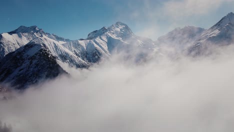 Drone-video-flying-through-the-clouds-towards-a-snowy-mountain-range