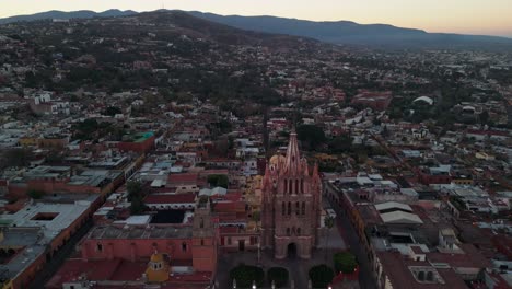 Eine-Drohne-Fliegt-Filmreif-Von-Der-Kathedrale-La-Parroquia-Weg,-Während-Die-Sonne-In-San-Miguel-De-Allende-Aufgeht
