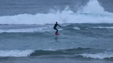 Surfer-on-hydrofoil-surfboard-riding-blue-ocean-wave