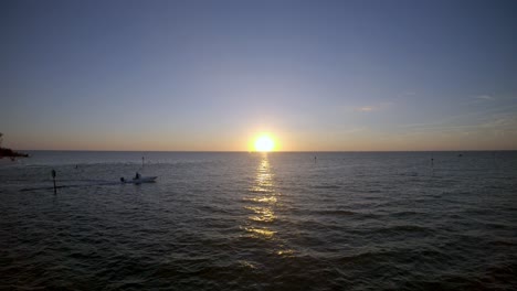 Aerial-4K-Drone-footage-of-a-Boat-sailing-across-the-Gulf-of-Mexico-with-the-sun-setting-behind