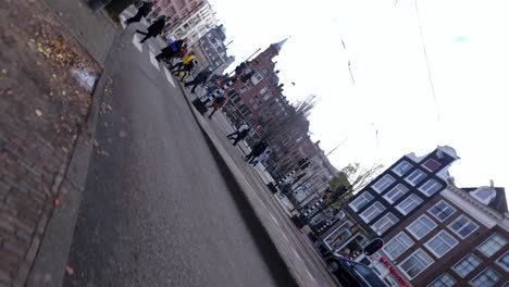 Vista-Giratoria-De-Peatones-Caminando-Por-Cruces-Peatonales-Durante-El-Día-En-El-Paisaje-Urbano-De-Ámsterdam,-Países-Bajos.