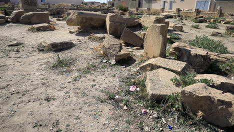 Sunlit-ancient-Roman-ruins-at-Sbeitla,-Tunisia-with-scattered-stone-blocks-and-greenery