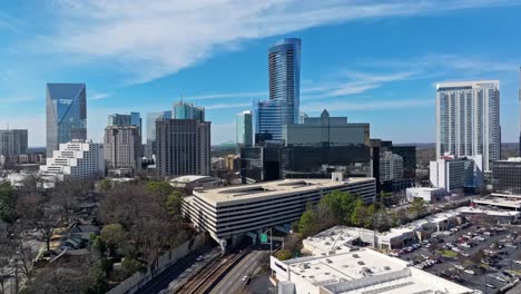 Aerial-flight-showing-cars-on-road-under-buildings-in-downtown-of-Atlanta,-Buckhead-in-sunlight