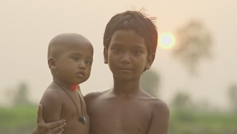 Una-Niña-Indígena-Sostiene-A-Un-Niño-Pequeño-Y-Sonríe-Durante-La-Puesta-De-Sol