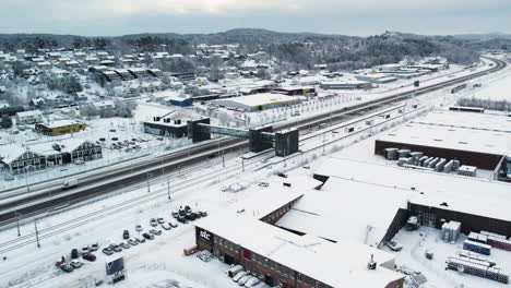 Aerial-view-of-Train-station-beside-highway-during-winter,-Alvangen-Sweden