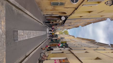 La-Gente-Camina-Por-Bares-Y-Tiendas-En-El-Callejón-De-Aix-en-Provence,-Vertical.