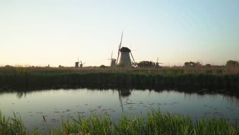 Holländische-Windmühlen-In-Ländlicher-Landschaft-Mit-See-Am-Frühen-Morgen