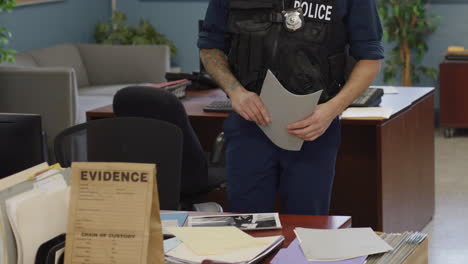 Close-up-hands-of-police-officer-going-over-documents-at-desk