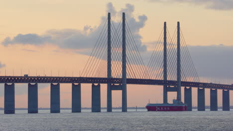 Crucero-En-Barco-De-Servicios-De-Autopistas-Marítimas-Europeas-K-Line-Bajo-El-Puente-De-Oresund,-Puesta-De-Sol