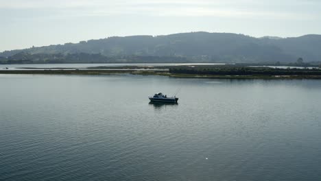 Orbiting-shot-over-Half-cabin-boat-with-fishing-rods-moored-on-lake-at-scenic-landscape