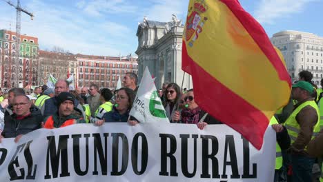 Spanish-farmers-and-agricultural-union-protesters-hold-a-banner-as-they-gather-at-Puerta-de-Alcalá,-in-Madrid-to-protest-against-unfair-competition-and-agricultural-policies