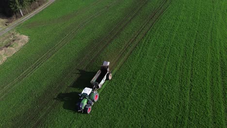 Luftaufnahme-Eines-Traktors,-Der-Mist-Auf-Eine-Grüne-Wiese-Sprüht