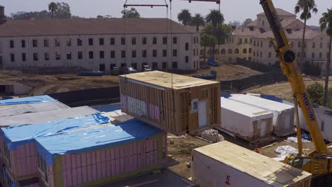 Close-up-push-in-aerial-shot-of-a-heavy-duty-crane-lifting-a-housing-module-unit-at-a-construction-site-in-West-Los-Angeles,-California