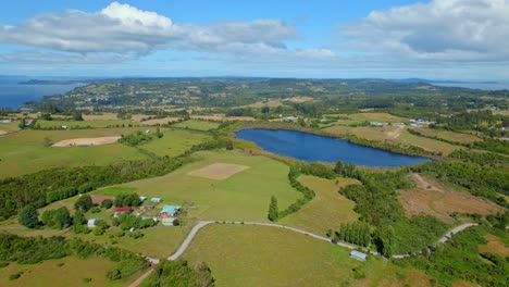 Isla-Lemuy-En-El-Archipiélago-De-Chiloé,-Que-Muestra-Paisajes-Vibrantes,-Un-Lago-Sereno-Y-Casas-Dispersas,-Vista-Aérea.