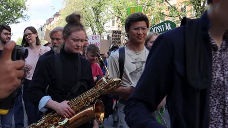 Young-musicians-march-with-instruments-at-climate-protest,-slo-mo