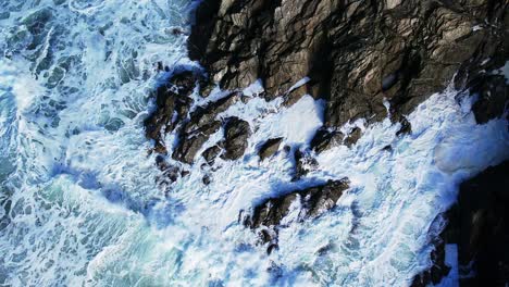 Meereswellen-In-Zeitlupe-Brechen-über-Die-Felsen-Von-Cornwall,-Mit-Draufsicht