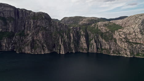 Wide-aerial-shot,-pushing-in-on-the-cliffs-beneath-Preikestolen,-by-Lysefjord-in-Norway