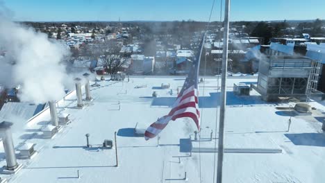 Smoke-from-smokestack-flying-around-american-flag-on-roof-of-building-in-american-Town