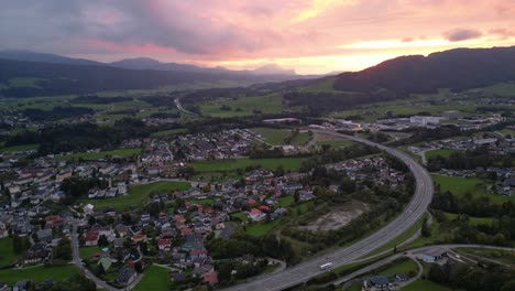 Autobahnstraße-In-Österreich-Mit-Rosa-Orangefarbenem-Himmel-Durch-Sonnenuntergang-Hinter-Den-Wolken---Luftaufnahme