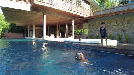 Children-playing-at-the-swimming-pool-area-of-vacation-house,-dynamic-handheld