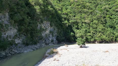 Drone-Volando-Sobre-La-Orilla-Del-Río-En-Muchas-Aguas,-San-Cristóbal,-República-Dominicana