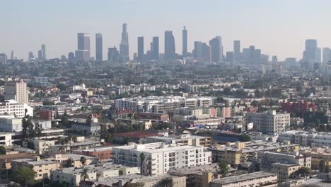 Aerial-view-of-cityscape,-residential-neighborhood-and-downtown-Los-Angeles-on-a-smoggy-day