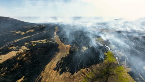 Rauch-Steigt-über-Frisch-Abgebrannter-Prärie-Auf,-Nach-Kontrolliertem-Brand-In-Den-Flint-Hills-Von-Kansas,-Drohnenaufnahme