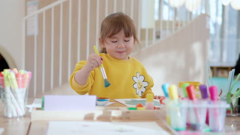 Glückliches-Kleinkind-Mädchen-Studieren-Zeichnung-Aquarelle,-Kleines-Fröhliches-Kind-Zeichnet-Mit-Farben-Und-Pinsel-Auf-Papier