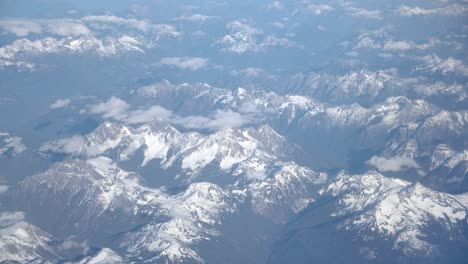 High-Up-Scenic-Airplane-View-of-Snow-Capped-Mountains-on-a-Sunny-Day