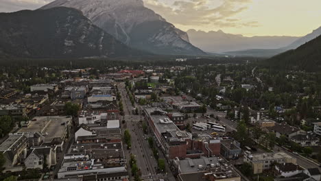 Banff-AB-Canada-Aerial-v12-cinematic-drone-flyover-town-center-capturing-quiet-morning-streets,-lush-forested-valley-and-Cascade-mountain-ranges-at-sunrise---Shot-with-Mavic-3-Pro-Cine---July-2023