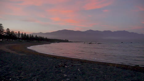 Slow-Motion-Pan-of-a-rocky-Bay-at-sunset-with-mountains-behind---Kaikoura,-New-Zealand