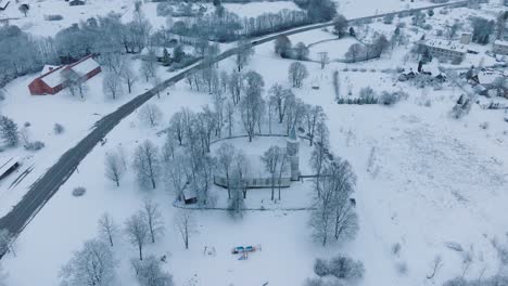 Paisaje-Cubierto-De-Nieve-Con-Caminos-Y-Colorido-Parque-Infantil-En-El-Pueblo-De-Renda,-Paisaje-Invernal,-Vista-Aérea,-Avanzando,-Inclinado-Hacia-Abajo