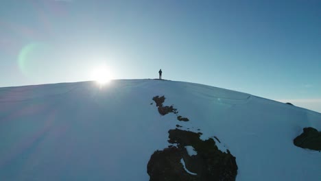 Una-Persona-Se-Encuentra-En-Una-Montaña-Nevada,-Con-El-Sol-Detrás-De-Ellos,-En-Francia.