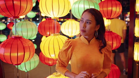 Attractive-Vietnamese-woman-in-traditional-yellow-dress-poses-with-colorful-lanterns-in-Hoi-An,-Vietnam