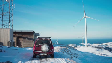 A-Vehicle-Parked-Close-to-Møllestua-with-Windmills-in-the-Background,-Against-the-Winter-Backdrop-in-Bessaker,-Trondelag-County,-Norway---Handheld-Shot